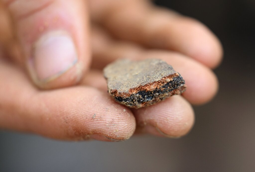Arqueólogo segura fragmento da laje de Saint-Belec.