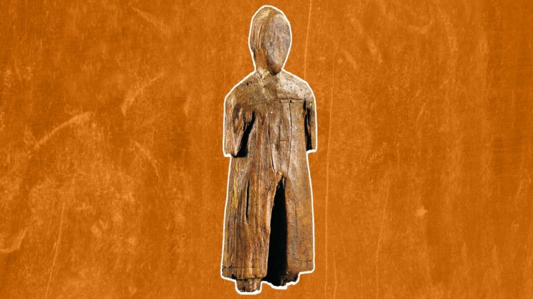 Estatueta de madeira esculpida de figura humana em pé, com braços ao longo do corpo e vestes longas, sobre fundo laranja.