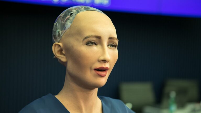 Rosto da robô humanoide Sophia, com pele artificial realista e parte de trás da cabeça transparente mostrando os circuitos
