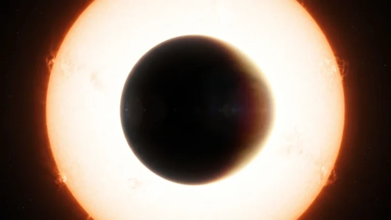 Silhueta escura de um planeta gigante levemente ovalado diante de uma estrela brilhante, com fino halo de luz na borda.